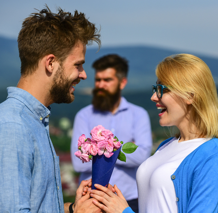 Lovers meeting outdoor flirt romance relations. Couple in love dating while jealous husband fixedly watching on background. Unrequited love concept. Couple romantic date lover present bouquet flowersの写真素材