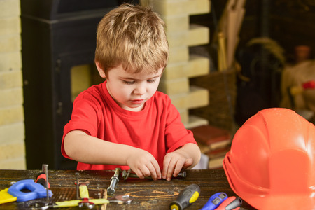 Kid fixing two metal details. Concentrated boy working with screw bolts. Preschooler helping in workshopの写真素材