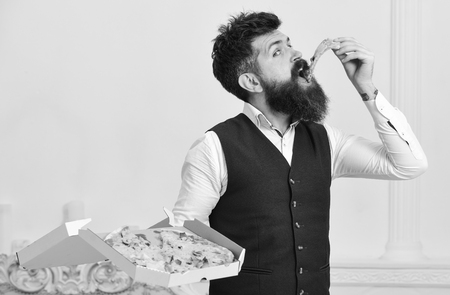 Pizza delivery concept. Man with beard and mustache holds delivered box with tasty fresh hot pizzaの写真素材