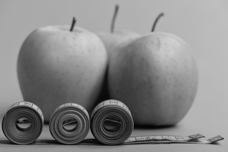 Apples near measuring tape rolls on green background, close upの写真素材