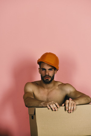 Guy with naked torso cardboard box. Seduction and moving concept. Man with beard isolatedの写真素材
