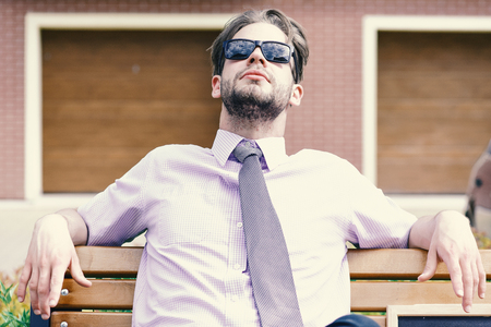 Adult businessman looking up wearing sunglasses on city street.の写真素材