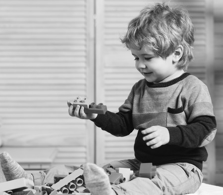Nursery game and childhood concept Boy plays with lego on wooden wall background.の写真素材