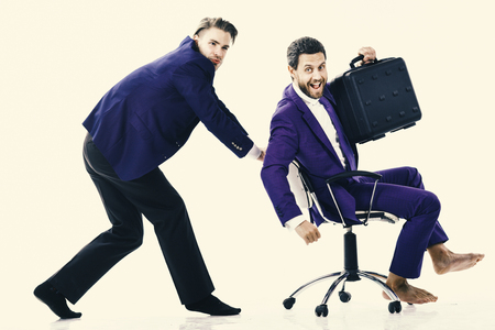 Man in suit or businessman pushing office chair with colleague with briefcase on, isolated on white background. Businessman got profit and celebrate success. Business and success concept. Businessman got profit and celebraの写真素材