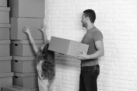 Kid and guy move into new home or move out Girl and man with busy faces on white wall backgroundの写真素材