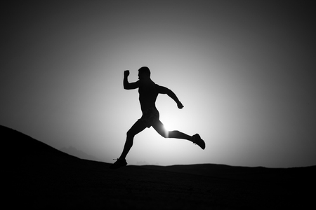 running man silhouette at sunset skyの写真素材