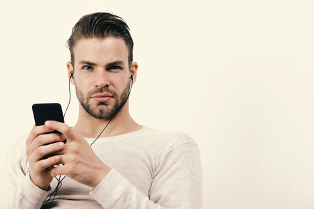 Man with smiling face with telephone. Guy with beard holds MP3 player and wears earphonesの写真素材