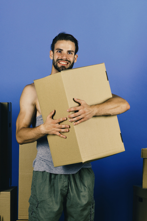 Delivery and moving in concept. Guy hugging carton and smilingの写真素材