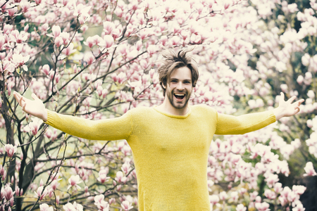 New life and optimism. Guy in yellow sweater with open hands on floral backgroundの写真素材