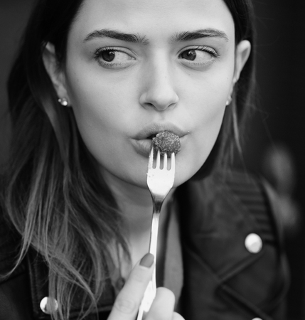 Nutrition and sweet life concept. Lady holds dessert fork with raspberry near mouth