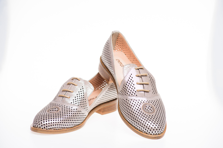 Shoes made out of silver leather on white background, isolated. Footwear for women on flat sole with perforation. Female footwear concept. Pair of fashionable comfortable loafer shoesの写真素材