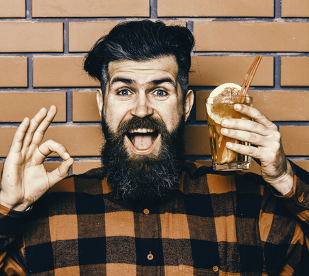 Delicious cocktails concept. Hipster enjoy drink or cocktail. Man shows ok gesture on brick wall background.の写真素材