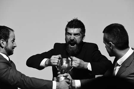 Businessmen with mad faces in formal suits on grey background. Coworkers or partners fight for...