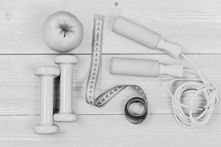 Dumbbells, measuring tape, jump rope and apple, top view. Barbells and centimeter near tools for weight loss. Workout and active lifestyle concept. Sports equipment on yellow backgroundの写真素材