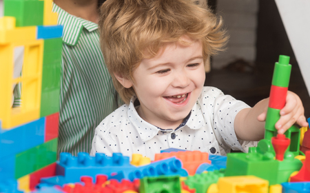 Baby boy looks at construction made out of colorful blocks.の写真素材