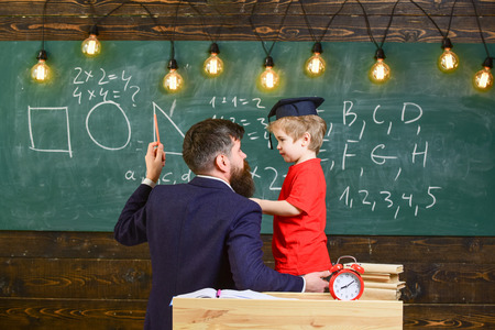 Instructive conversation concept. Teacher with beard, father teaches little son in classroom,...