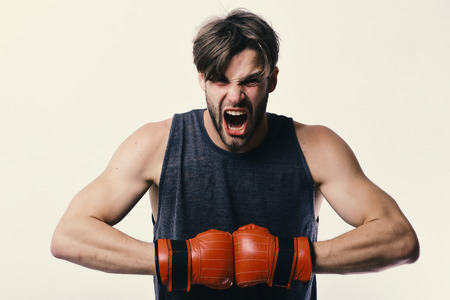 Man with bristle and furious face wears boxing gloves. Boxer makes hits and punches as training. Sports and competitionの写真素材