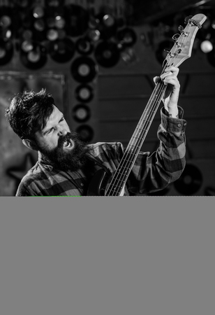 Musician with beard play electric guitar on stage. Young rock musician, singer, talented artist. Man with busy faceの写真素材