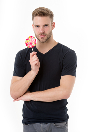 Guy with lollipop isolated on white. Man with candy on stick. Fashion macho with swirl caramel in casual tshirt. Sweet food and dessert. Unhealthy diet and eatingの写真素材
