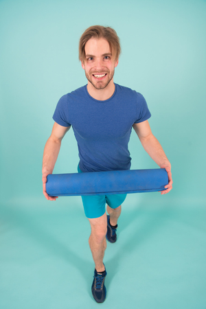 Pilates. Happy sportsman smile with yoga mat. Fashion athlete in sportswear. Healthy lifestyle and dieting. Man with stylish bristle and hair. Gym equipment for training and workout. Time for yogaの写真素材