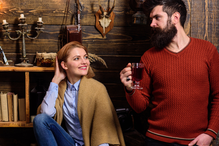 Couple spend pleasant evening, interior background. Woman and man on smiling faces enjoy cozy atmosphere with hot drinks. Coziness concept. Family, couple in love enjoy vacation in gamekeepers house.の写真素材