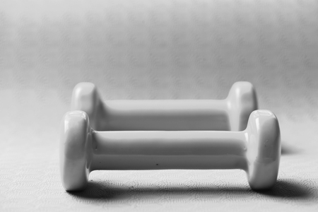 Dumbbells in cyan blue color on purple background, selective focus. Barbells made of plastic, close up. Shaping and fitness equipment. Sports and healthy lifestyle concept.の写真素材