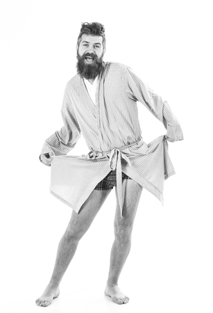 Man with smiling face in good mood on white background. Slept well concept. Guy stand in bathrobe, dancing or posing in morning, copy space. Hipster with beard and mustache holds bathrobe like dress.の写真素材