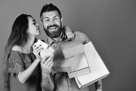 Shopping and free time concept. Man with beard holds credit card and piggy bank.の写真素材