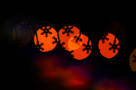 Christmas holiday decoration with silhouette of snowflake. Lights of colorful garland blurred as beautiful background. Lights of christmas garland blurred on black background. Christmas conceptの写真素材