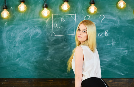 Lady sexy teacher looking back while explaining formula. Sexy teacher concept. Teacher of mathematics writing on chalkboard, rear view. Woman with nice buttocks teaching mathematics, copy spaceの写真素材