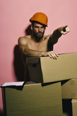 Sexuality and moving concept. Guy with sexy torso stands naked behind boxesの写真素材