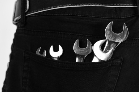 Wrench tools in jeans pocket on white background. Spanner equipment made of metal. Repairer or mechanic costume with spanner instruments. Maintenance and repairing concept.の写真素材