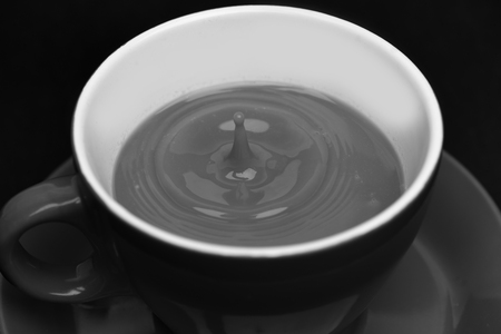 Coffee making concept. Fresh brewed coffee poured into cup with splashes. Red ceramic mug pouring, filling with coffee, sackcloth background.の写真素材