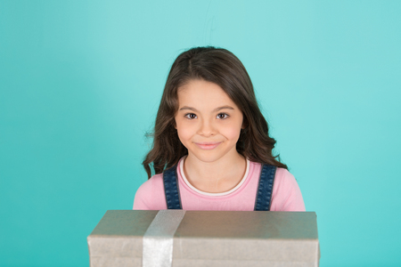 Wish list. Girl dreaming about amazing gift. Child happy face holds big gift box turquoise background. Girl curly hairstyle adorable happy face celebrate birthday. Kid happy loves birthday giftsの写真素材