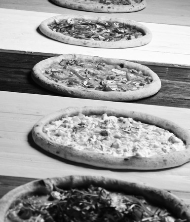 Take away food with various ingredients and crunchy edges. Different pizzas set for menu. Pizza circles with meat, mushrooms, tomatoes and cheese on wooden background. Italian pizza and taste concept.の写真素材