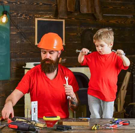 Boy, child cheerful holds bolts or screws, having fun while handcrafting with dad. Father, parent...