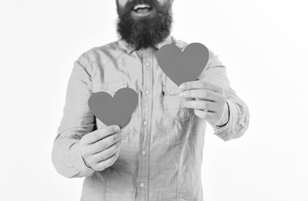 Love and romantic feelings concept. Man with beard and happy face shares his romantic feelings by symbol of love - red heart. Hipster in denim shirt holds red heart, isolated on white background.の写真素材
