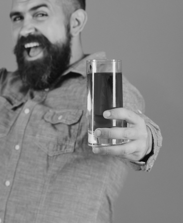 Farmer with happy face holds fresh apple juice, close up. Farming and autumn products concept. Man with beard holds tasty juice on blue background, defocused. Guy presents homegrown harvestの写真素材