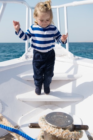 Cute and carefree. Adventure boy sailor travelling sea. Child cute sailor on yacht sunny day. Boy adorable sailor striped shirt white yacht travel around world. Baby boy enjoy vacation on cruise shipの写真素材