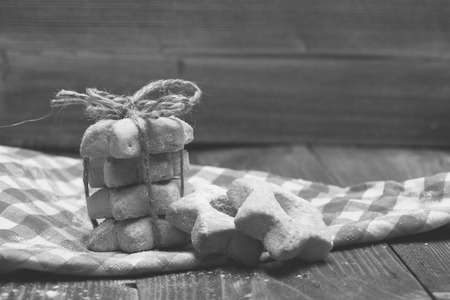 Star shaped biscuits tied in pyramid on red cloth. Homemade pastry concept. Composition of tiny gateau and metal biscuit form on plaid kitchen towel. Tea cookies on wooden background.の写真素材