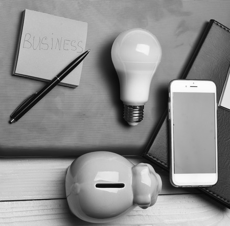 Business and profit concept. Home office composition. Moneybox near organizer, pen, sticky notes,...