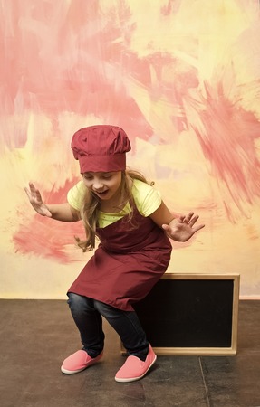 little happy chef sitting on blank cook restaurant menu board on colorful background, copy spaceの写真素材