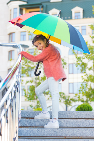 Girl standing on stairs and holding umbrella. Autumn rain. Waiting for bad weather under umbrella. Stylish girl in downtown. Positivity as resistance to cold. Beautiful lady going for a walk.の写真素材