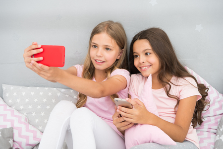 Online entertainment. Explore social network. Smartphone for entertainment. Kids taking selfie. Smartphone application concept. Girlish leisure pajama party. Girls smartphone little bloggers.の写真素材