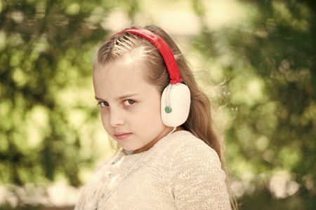 Cute little girl enjoying music using headphones at summer dayの写真素材