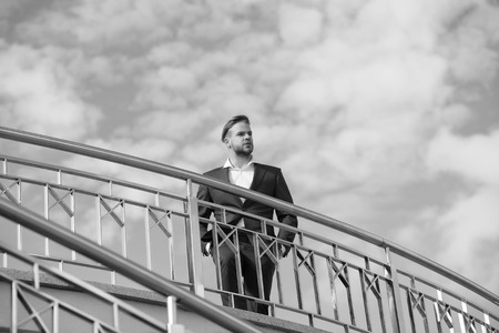 Businessman attractive appearance looks successful. Freedom concept. Man confident and well groomed enjoy freedom. Businessman successful entrepreneur in suit walks outdoor sunny day, sky background.の写真素材