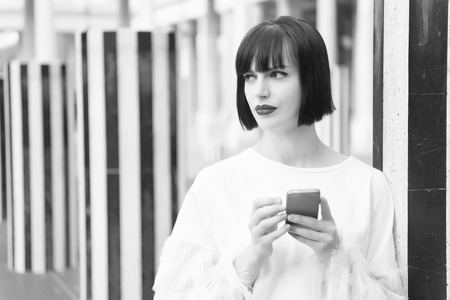Beauty girl with sexy look in paris, france. Woman with red lips use on smartphone. Woman with brunette hair hold mobile phone. Fashion model with mobile device. New technology for modern life.の写真素材