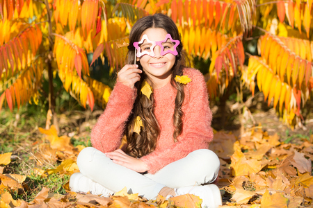 Its all a masquerade. Little child hold fake glasses on face. Girl child have fun on autumn day. Little child full of play. Autumn holidays. Naughty and cute.の写真素材