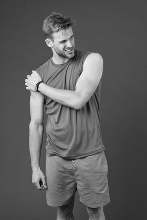Sportsman touch shoulder on violet background.の写真素材