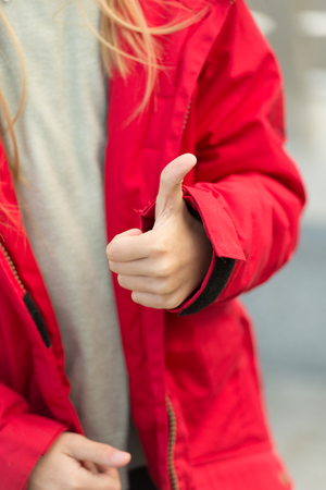 Hand of baby shows thumbs up gesture. Kid wear warm jacket show gesture of  accept.の写真素材